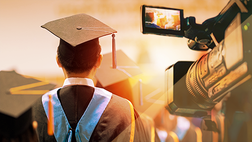student wearing a cap and gown with a video camera recording the event